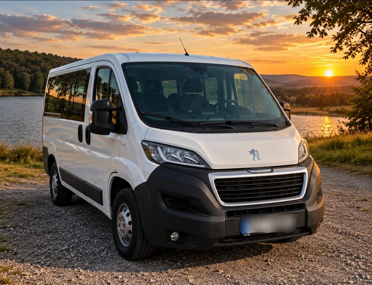 Bílý devítimístný Peugeot Boxer u jezera při západu slunce